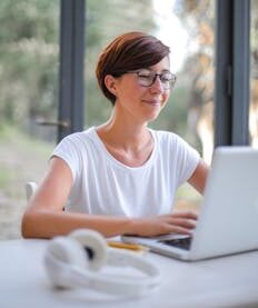 A happy woman with short hair using a laptop indoors, showcasing remote work lifestyle.